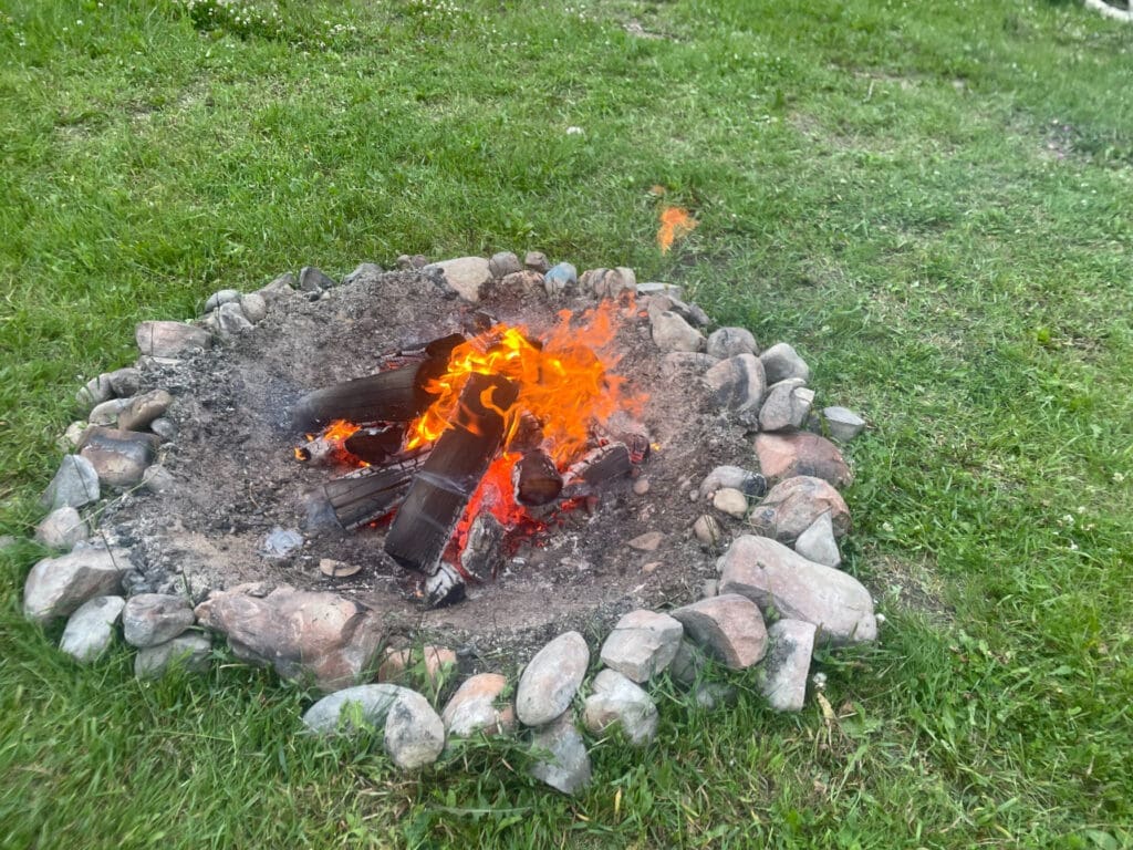 A dug-out fire pit fire with rocks and dirt around it to set up a campfire safely.